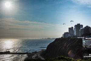 Two paragliders suspended above ocean bluff outside Lima, Peru. 