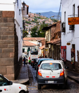 Cars and buses making their way down a narrow street in Peruvian city.