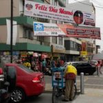 Lima street showing small shops, banners and man with bicycle cart.