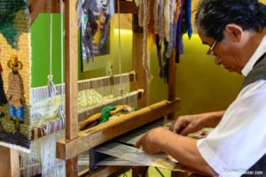 Male Peruvian artisan demonstrating modern weaving techniques.